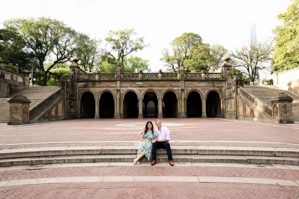 Circular brick terrace with stone benches and architectural details surrounded by green lawn and trees.