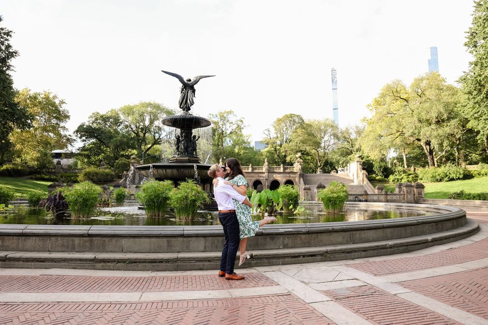 Wide view of a landscaped park area with fountain, brick walkways and manicured gardens.