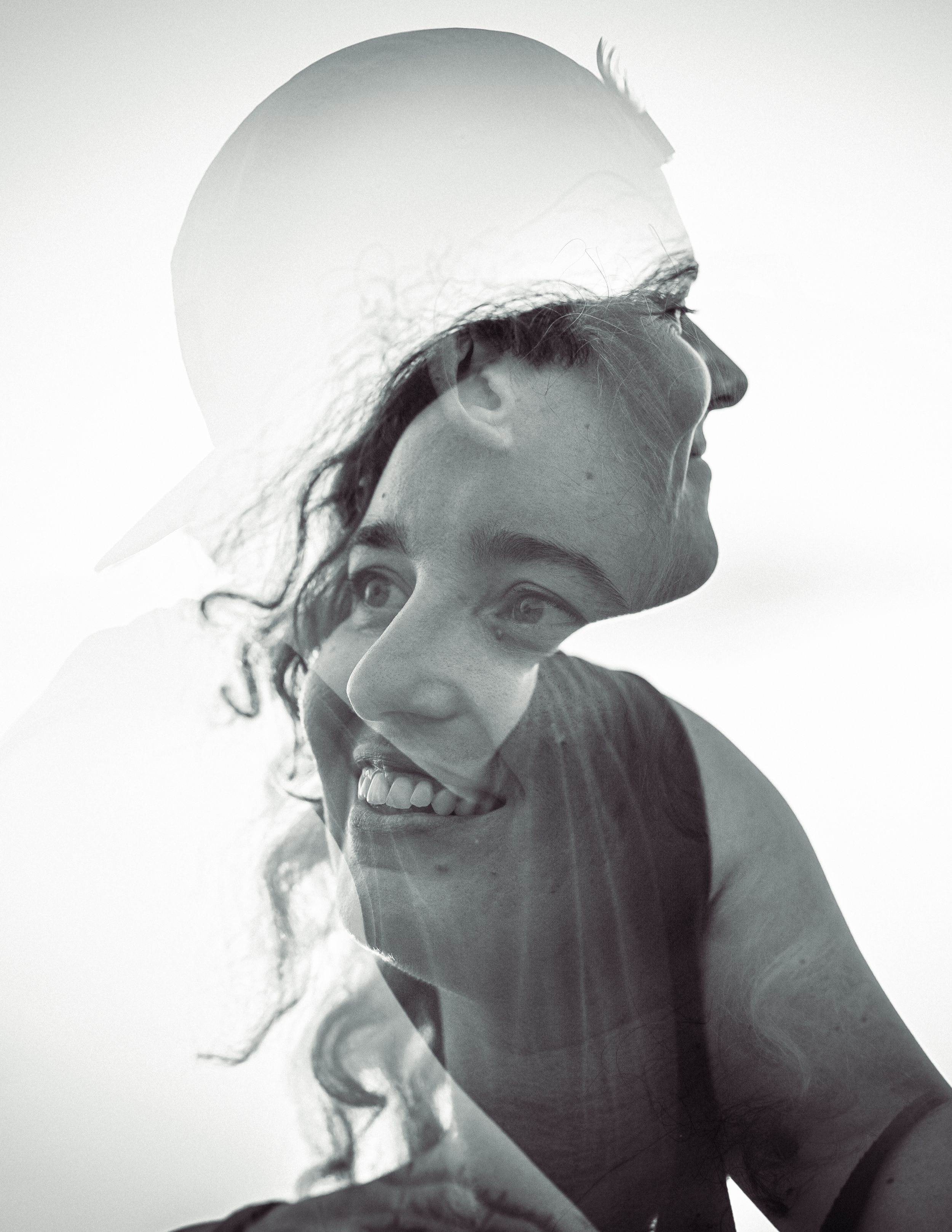 A black and white double exposure portrait of a smiling young woman merged with a silhouette profile image.