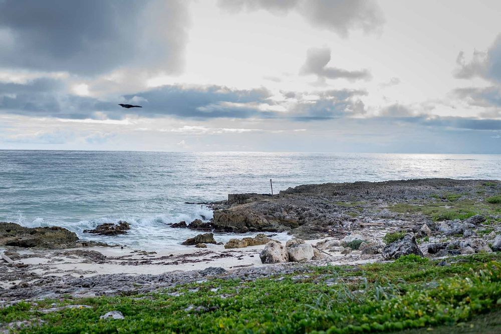 Panoramic view of rocky coastline with ocean waves and cloudy sky.