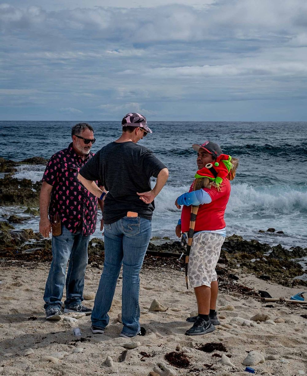 Tourists observing the rocky shoreline and ocean waves on a cloudy beach day.