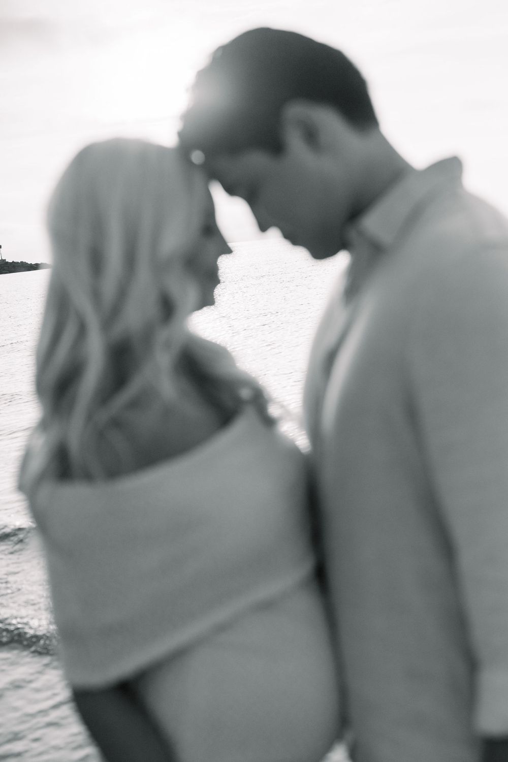 A series of black and white photos showing a couple embracing at the beach.