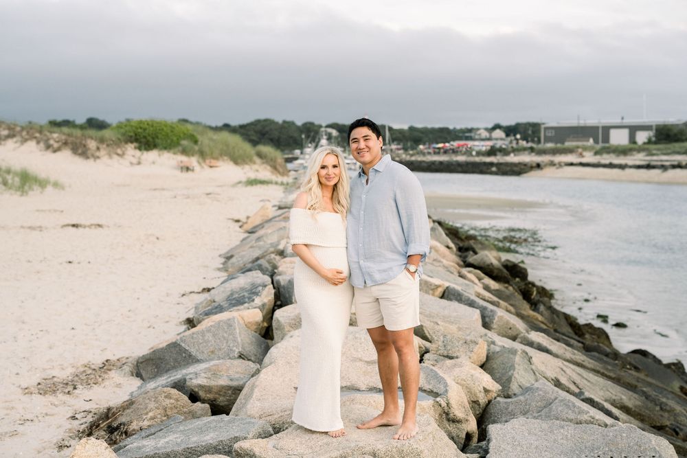 A couple shares romantic moments on a rocky beach during their coastal wedding photoshoot.