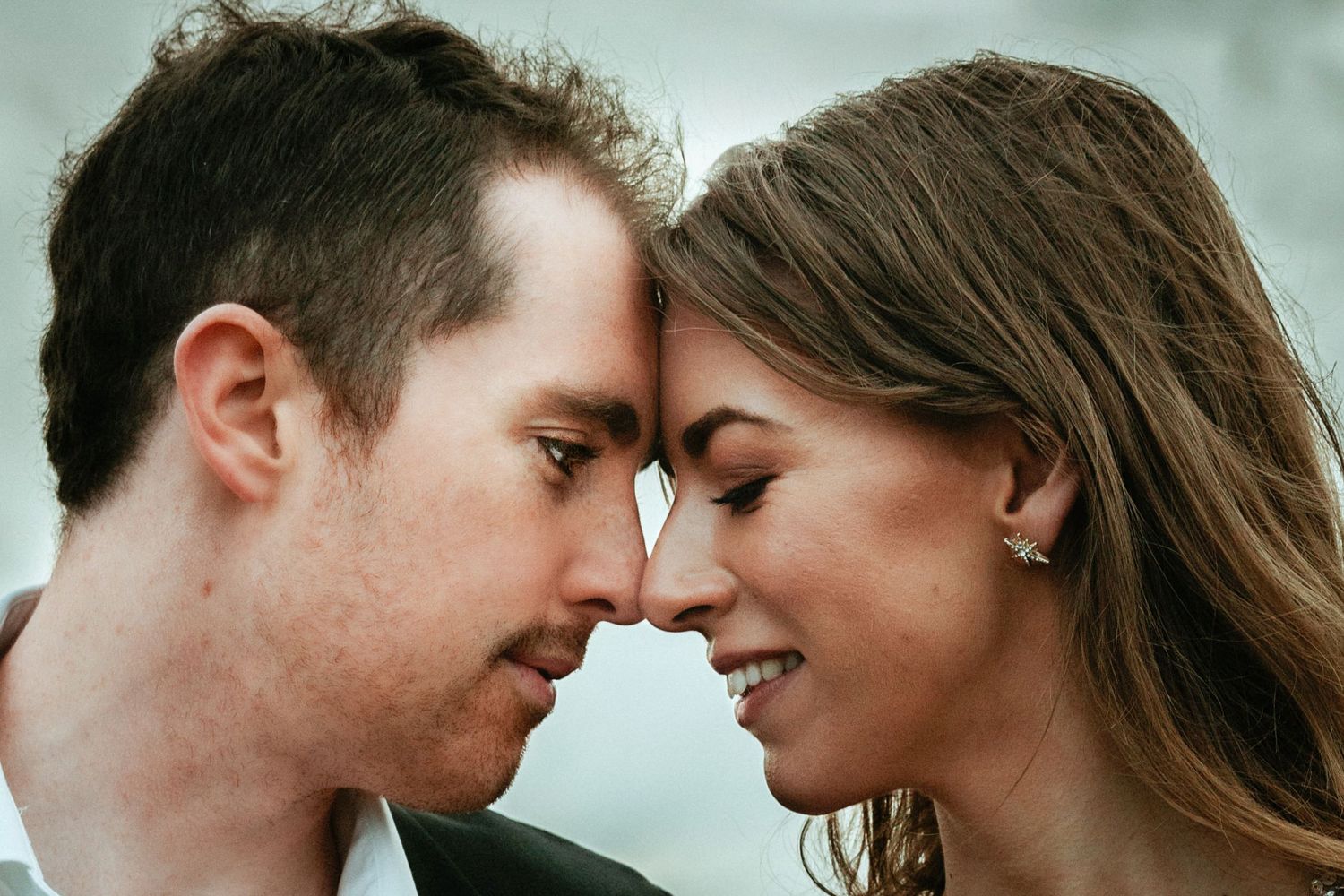 Man gazes at woman during romantic engagement session.