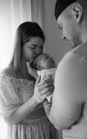 Ervaren newborn fotograaf legt ontspannen baby vast in uitgebreide newbornshoot met oog voor veiligheid Eindhoven Noord-Brabant
