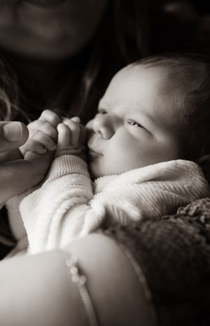 Newborn fotograaf legt ontspannen baby vast tijdens uitgebreide en natuurlijke newbornshoot Eindhoven Noord-Brabant