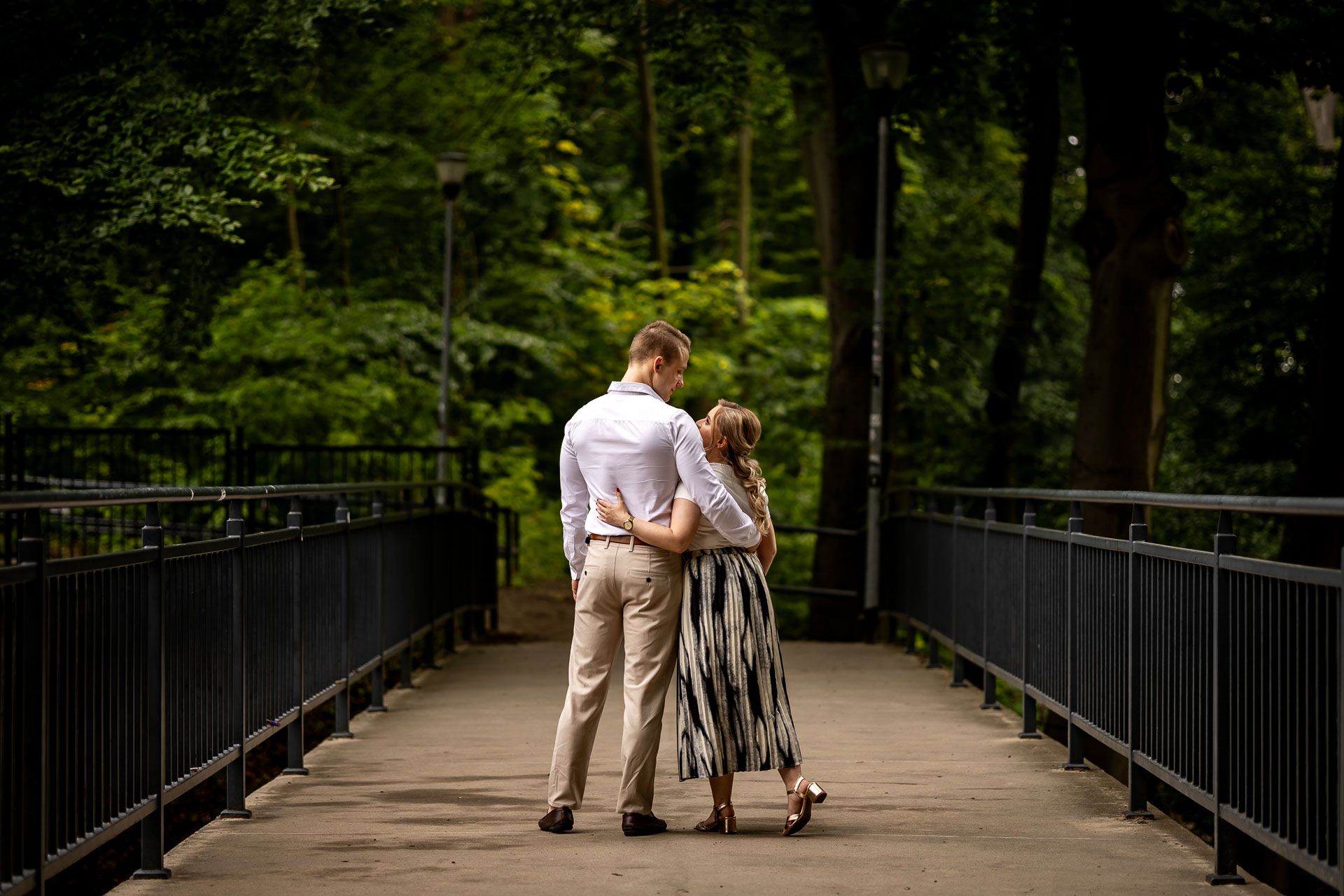 Long pedestrian bridge through lush green forest creating a romantic walking path.