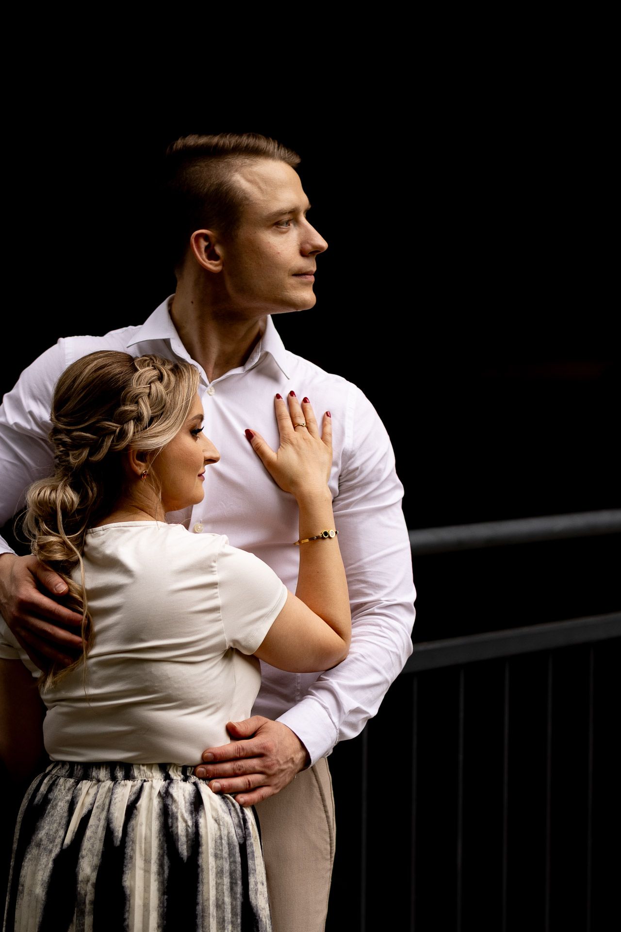 Intimate black and white portrait of a couple embracing against dramatic lighting.