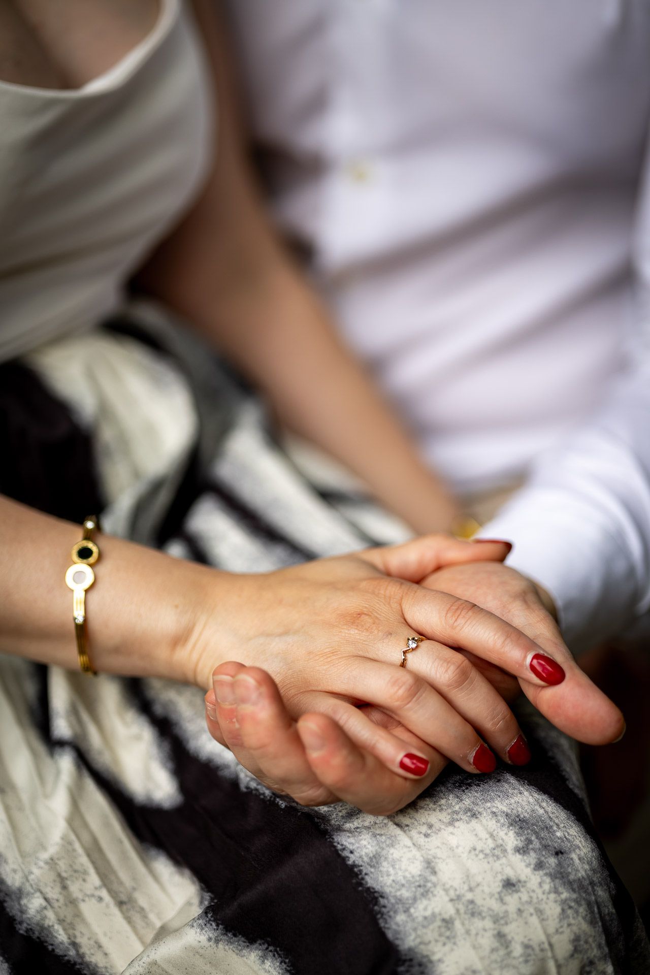 Close-up of hands with red nail polish touching on a striped fabric surface.