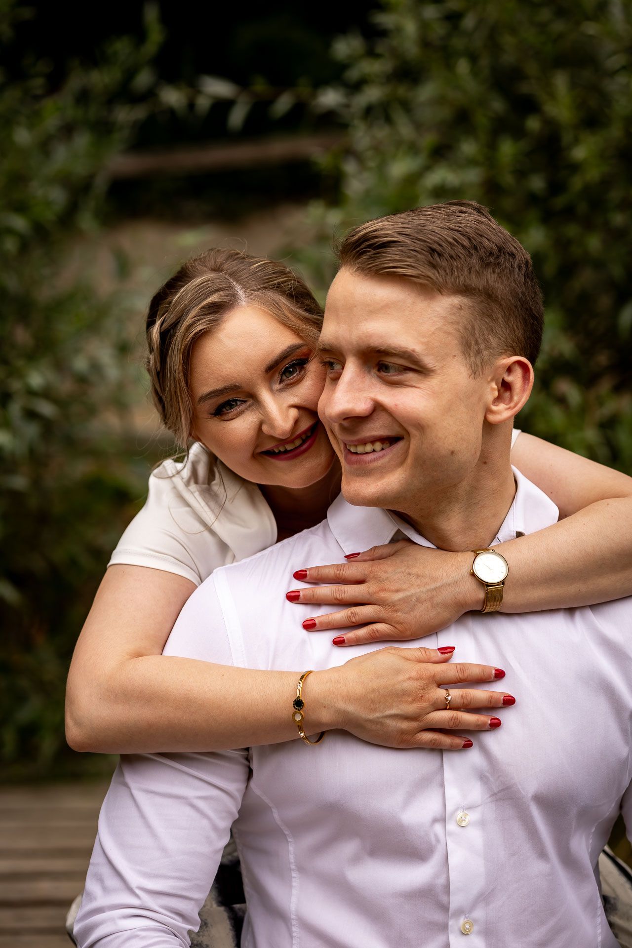 Playful couple in white shirts sharing joyful moments outdoors.