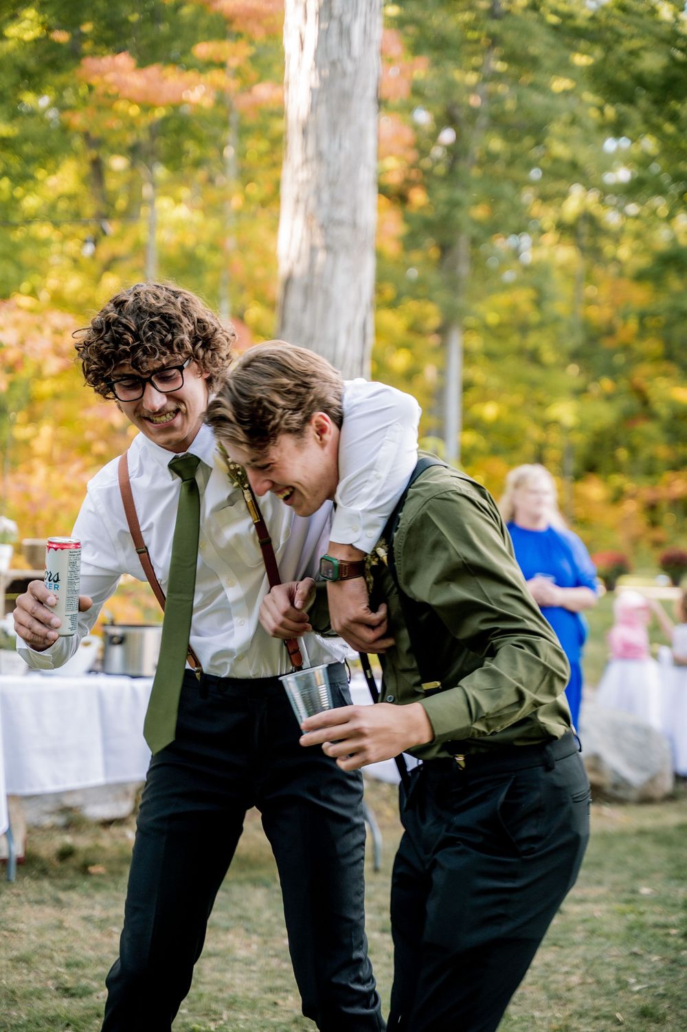 Two people in vintage attire share a playful moment laughing together in an outdoor autumn setting.