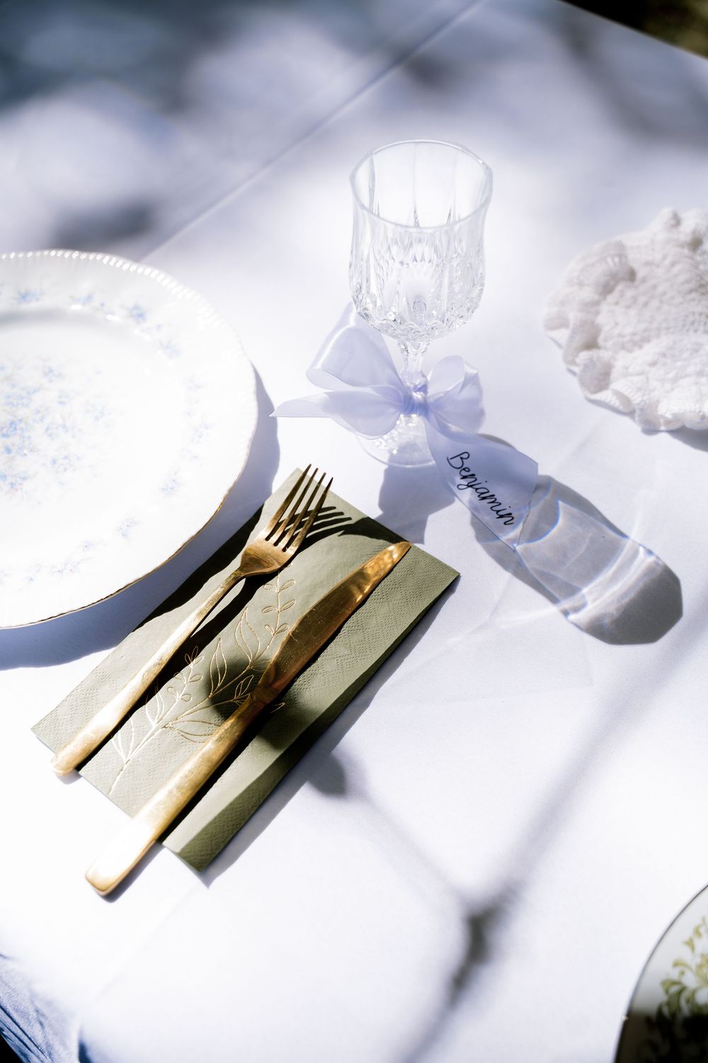 Elegant place settings with white napkins and gold utensils arranged on a rustic wooden surface.