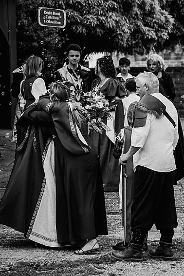 Black and white photo of people in historical costumes gathered outdoors in a line formation.