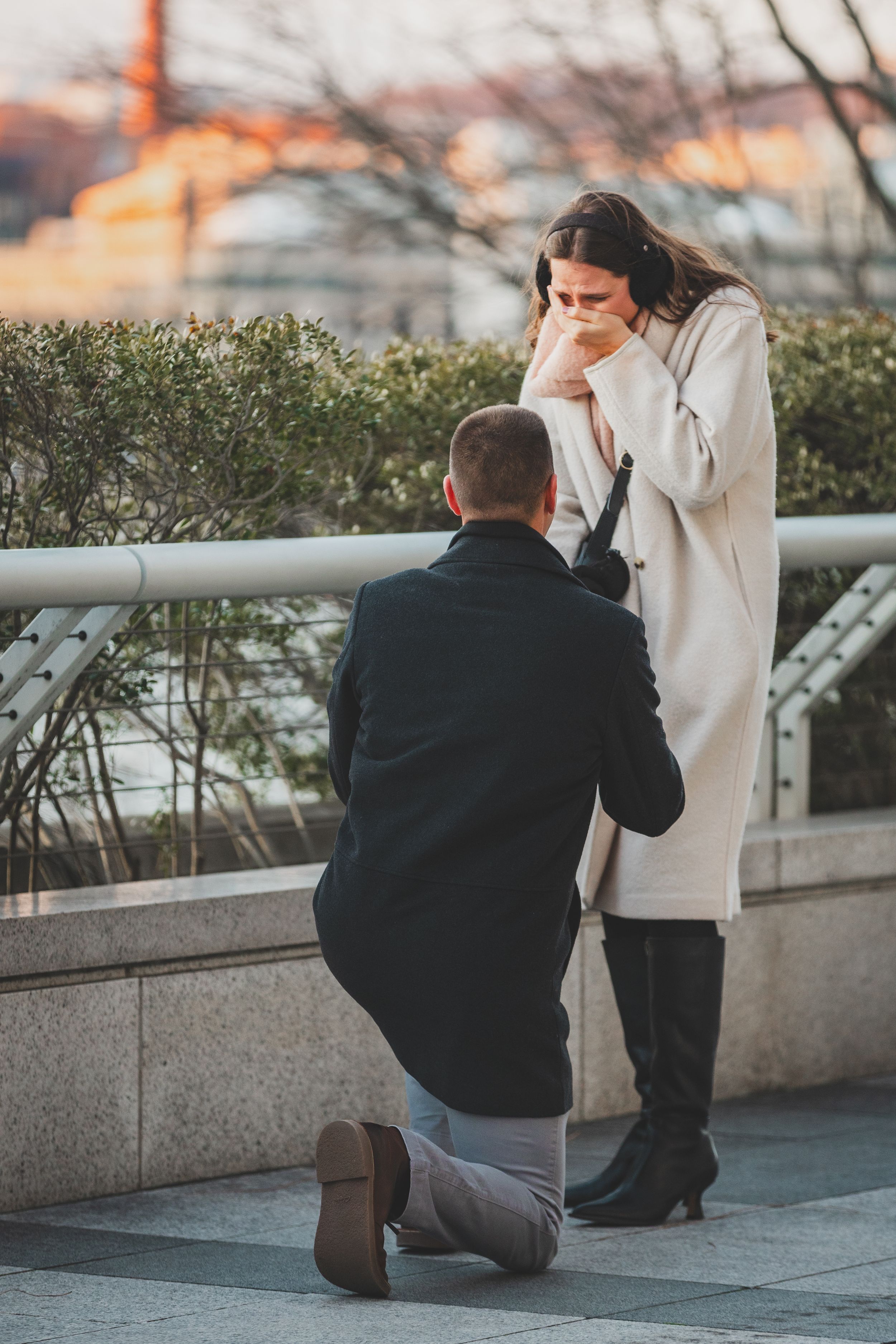 A proposal sequence showing someone kneeling  on a city terrace during sunset at the Kennedy center, a great Dc winter proposal location