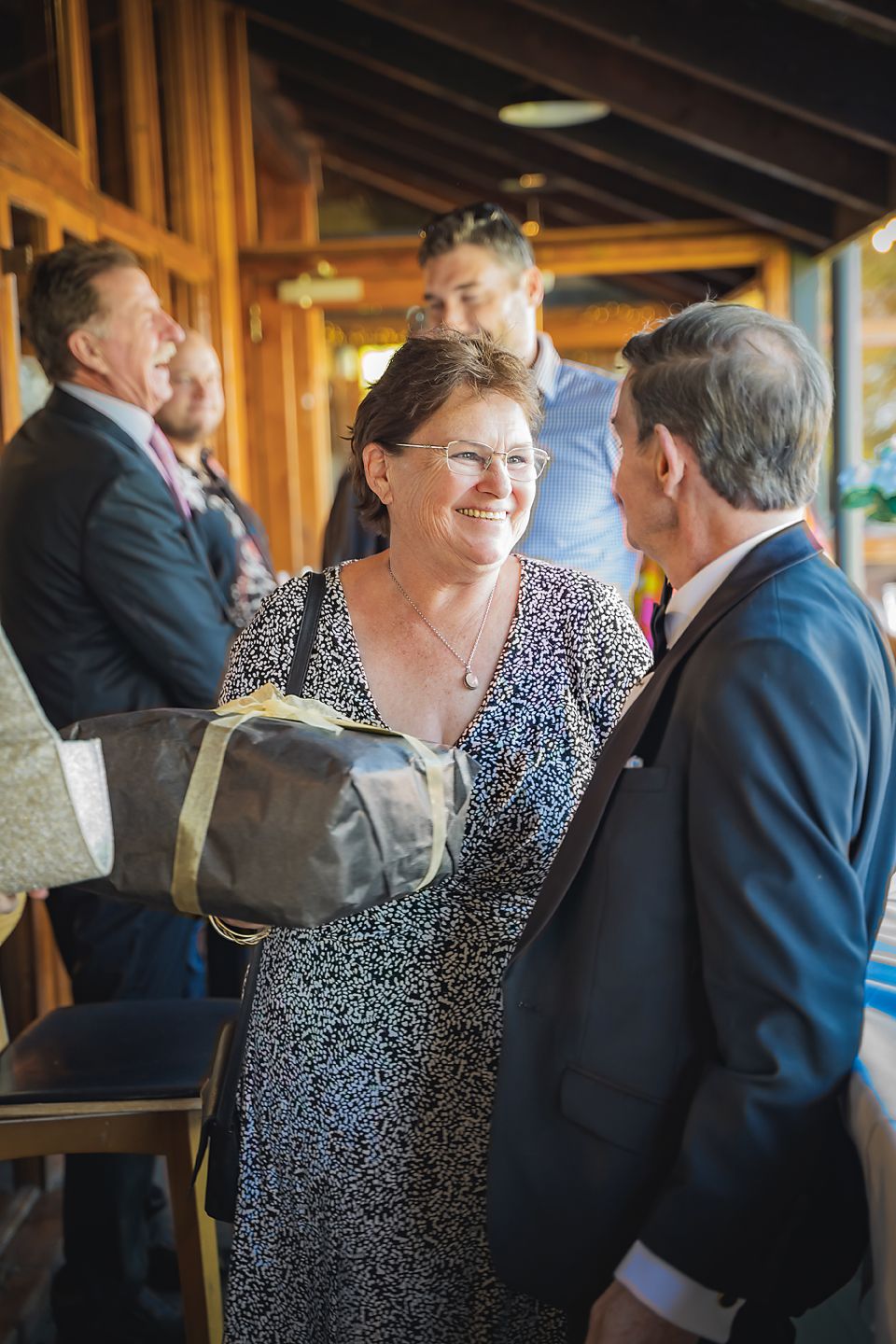 A candid moment at an indoor gathering shows people in formal attire engaged in lively conversation.