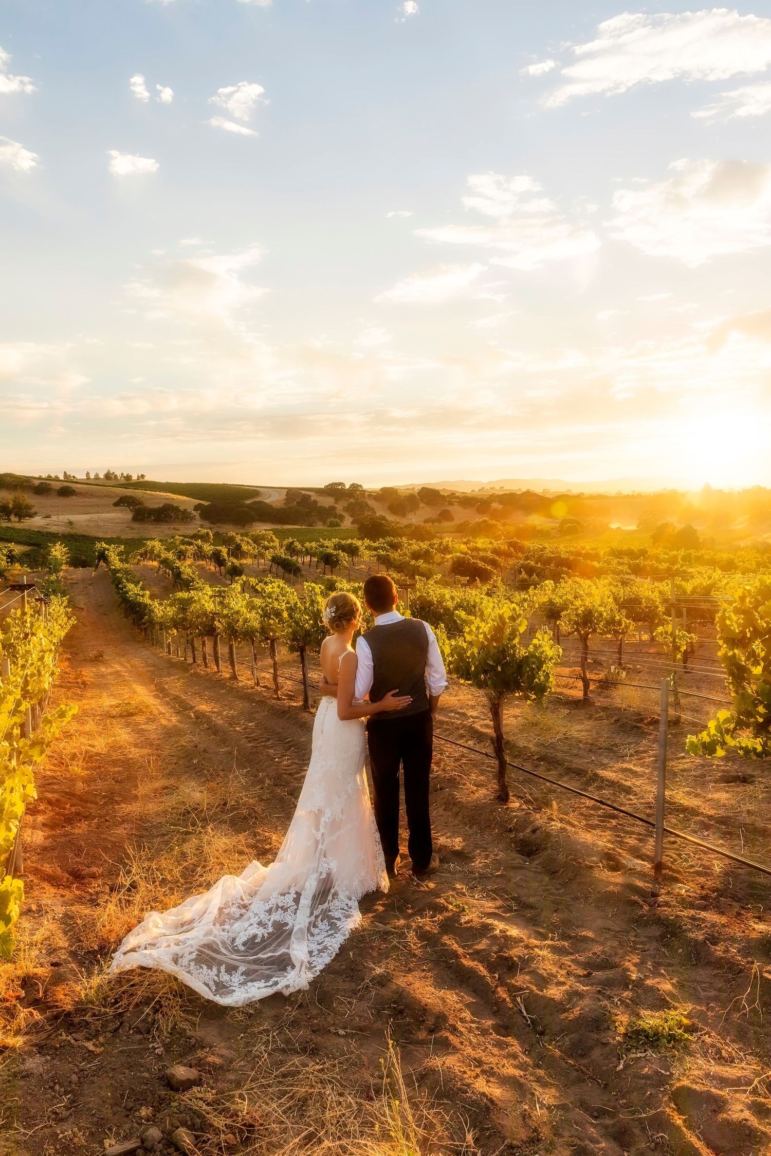 A photographer captures sunset photos on a rocky cliff overlooking a scenic landscape at golden hour.