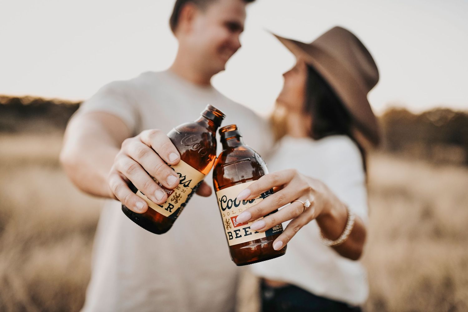 Editorial-style engagement photos of a couple having fun with beer and movement