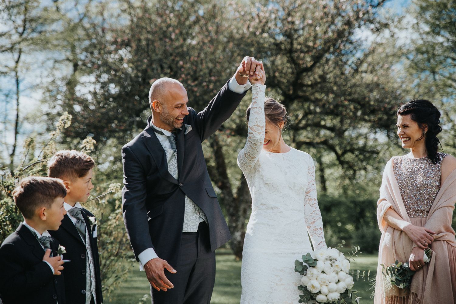 Outdoor wedding celebration with guests and wedding party in natural setting.