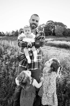 Black and white portrait of family interaction in a wildflower meadow.