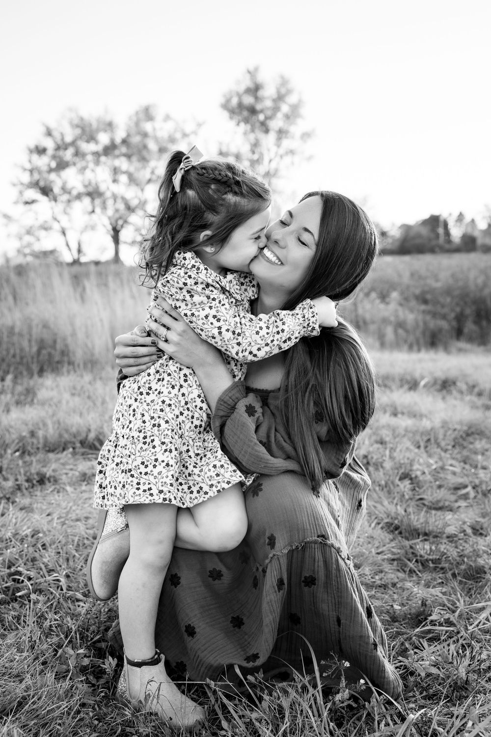 Black and white photo capturing tender moment in an outdoor field setting.