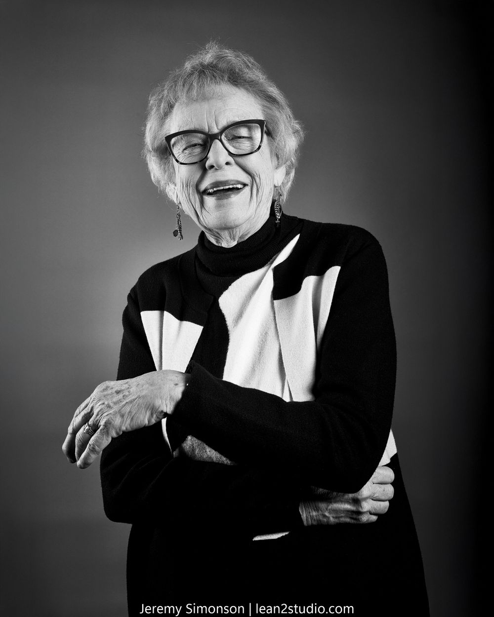 Black and white portrait series showing joyful expressions and laughter against dark background.
