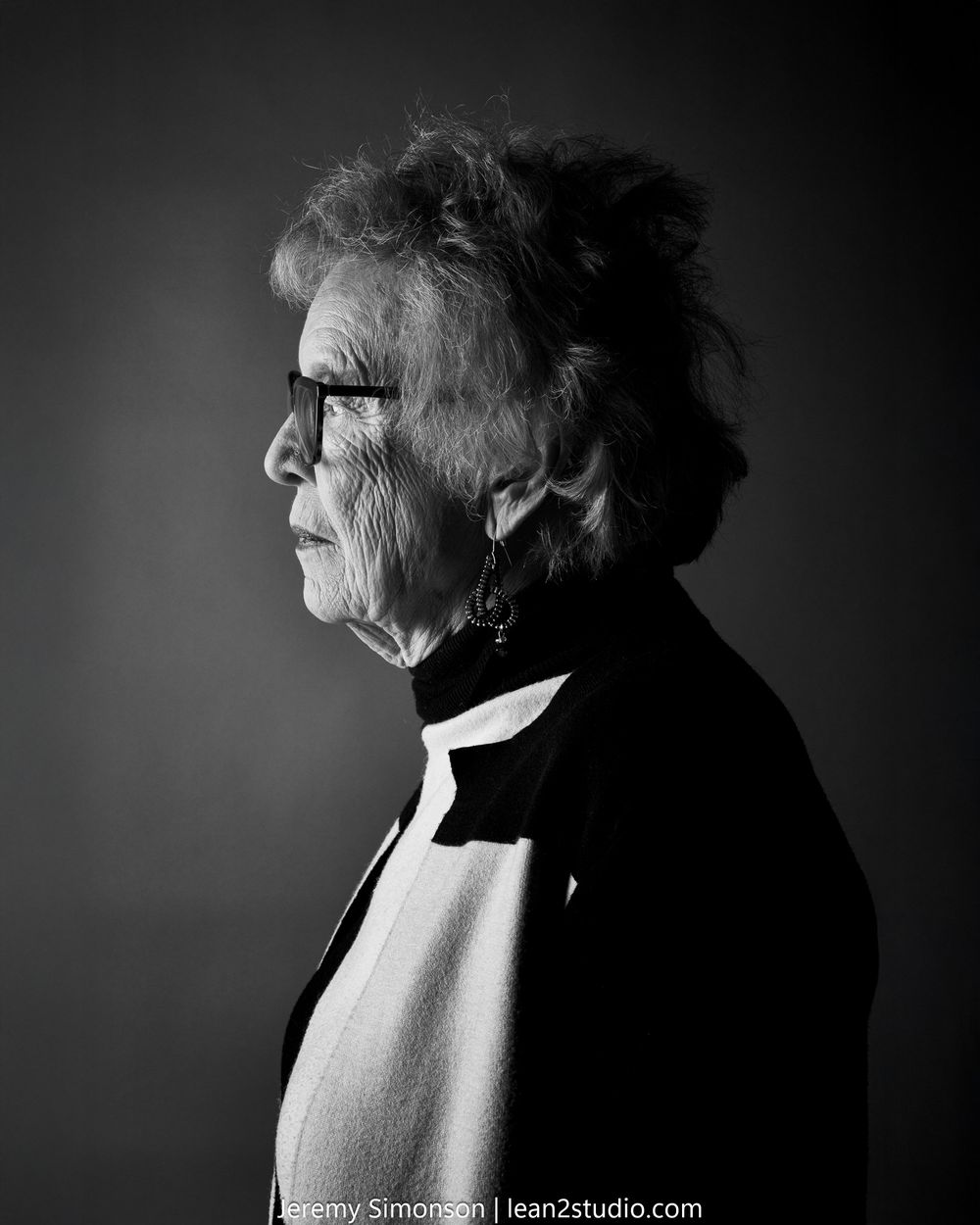 Dramatic black and white portrait profile series showing an elderly figure in a dark turtleneck against a black background.