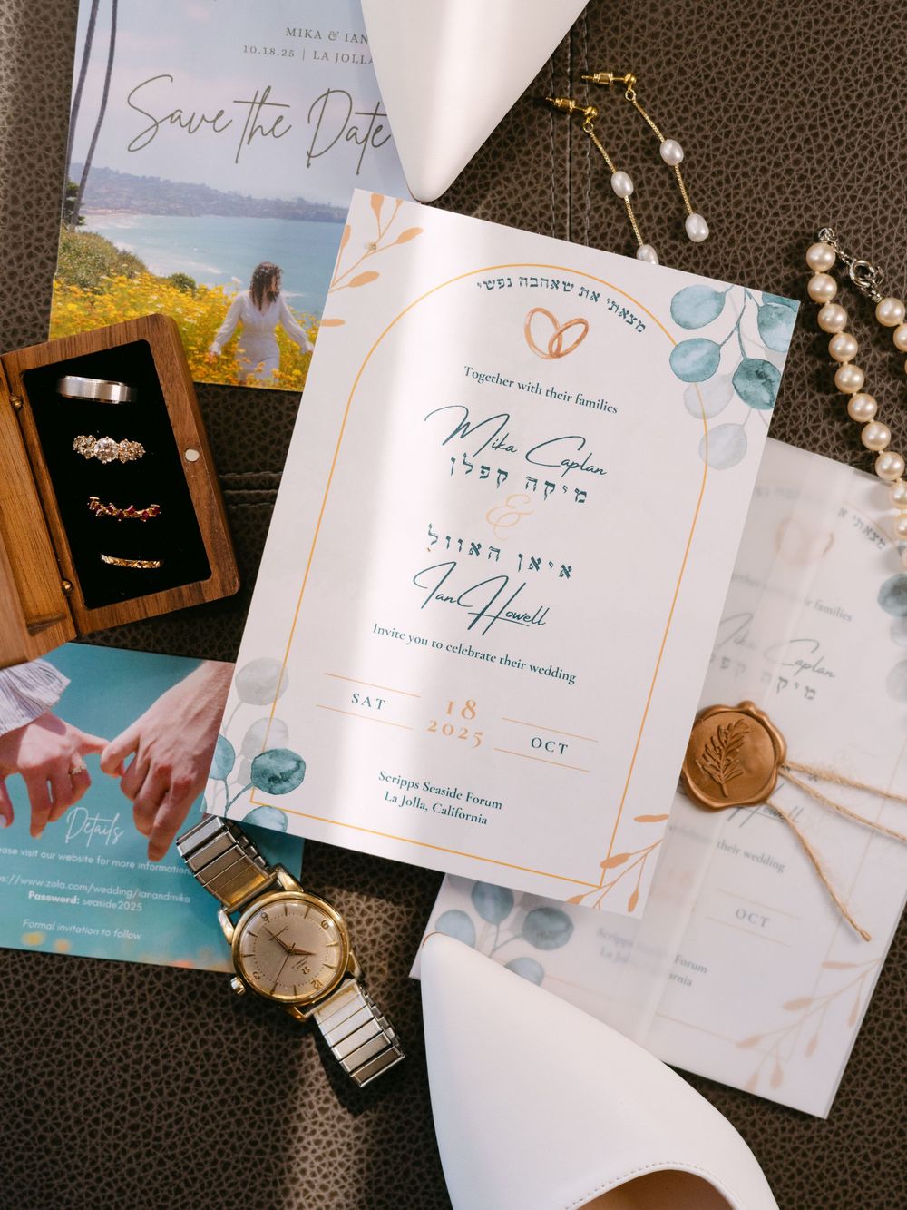 Elegant wedding invitation suite with floral designs and gold accents displayed on dark textured background.