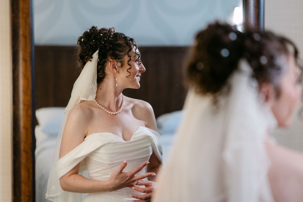 A bride and bridesmaid share an emotional embrace during a wedding preparation moment.