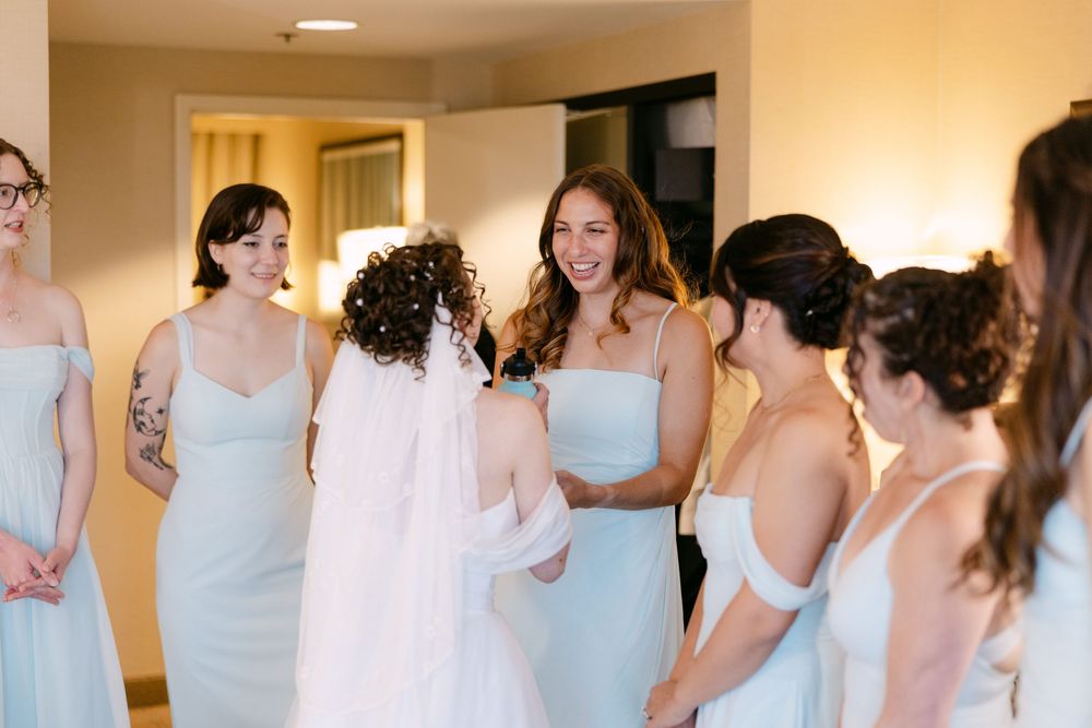 A group of bridesmaids in light blue dresses gather together in preparation for a wedding ceremony.