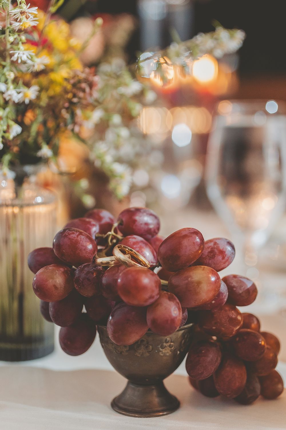 Fresh red grapes arranged in decorative glass bowls create an elegant table centerpiece with soft bokeh lighting.