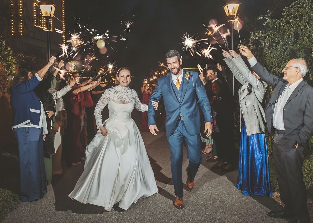 Wedding guests dance and celebrate during an outdoor evening reception under twinkling lights.