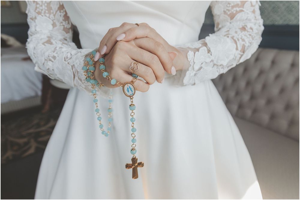 Close-up details of delicate white lace sleeves and hands holding a decorative key pendant on a chain.