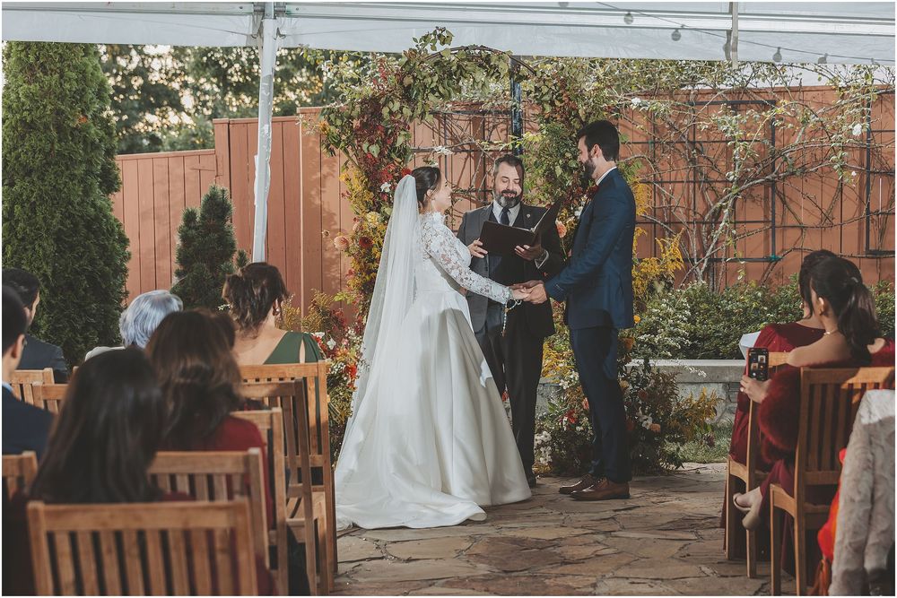 Wedding guests gather in a garden courtyard during an intimate outdoor ceremony celebration.