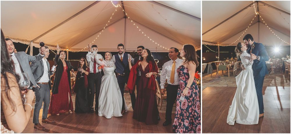 Wedding guests dancing and celebrating together on a lively dance floor under a white tent during an evening reception.