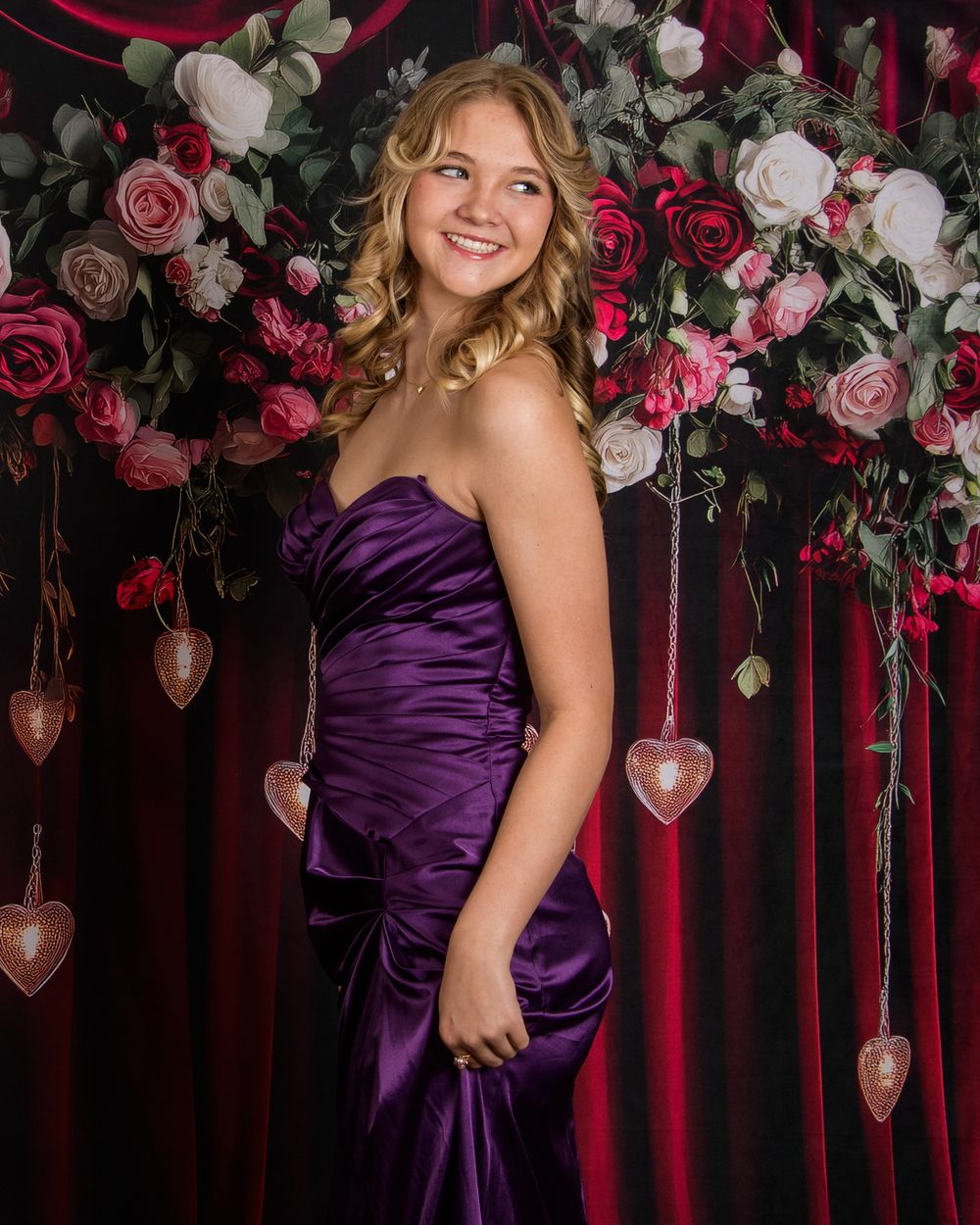 A series of four photos showing someone in an elegant deep purple satin gown posing against a floral backdrop with roses.