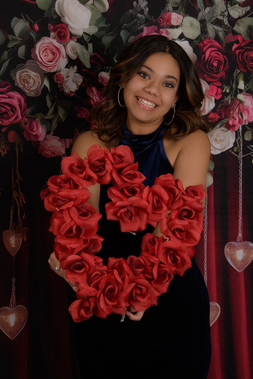 A beautiful red rose heart-shaped wreath displayed against a dark background with pink roses and crystal accents.