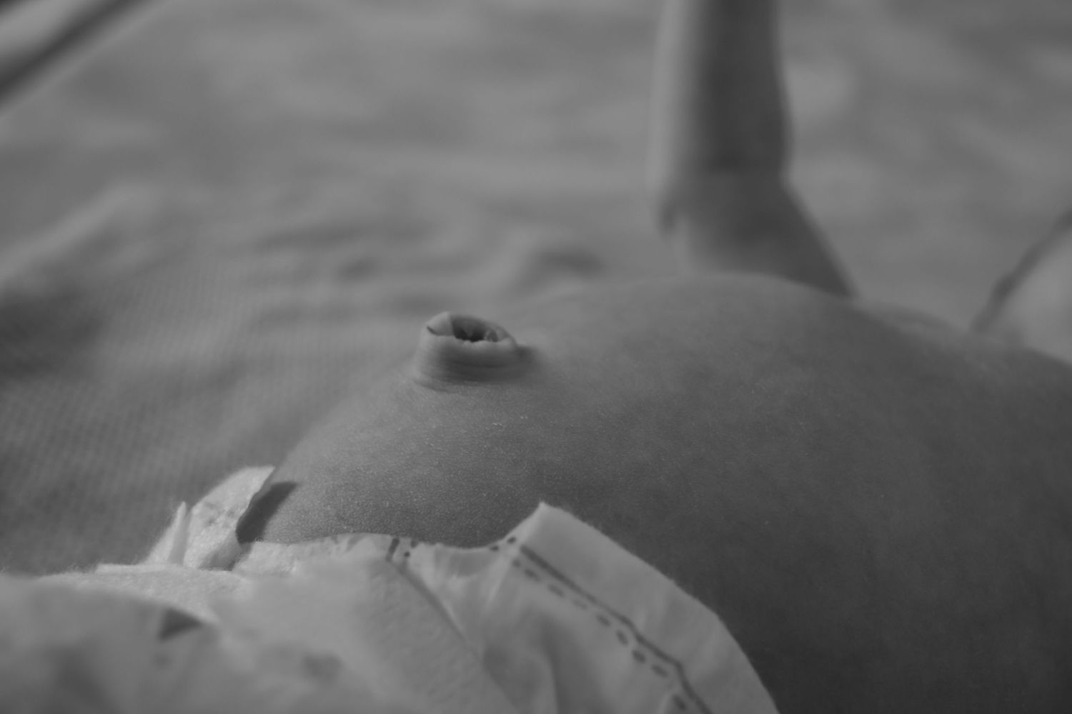 A black and white close-up photograph of a baby's belly at a central coast newborn photoshoot.
