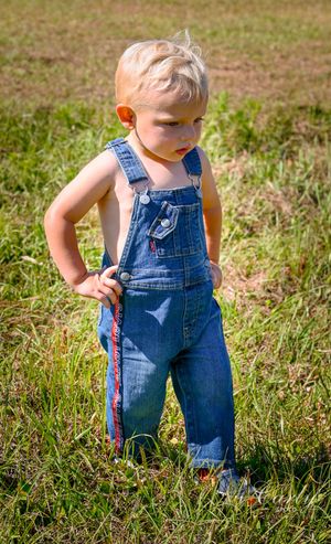 A sequence of close-up shots showing small feet in denim overalls walking through green grass on a sunny day.