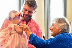 Three generations share a tender moment together by a window in natural lighting.