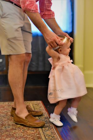 A sequence of feet showing someone helping a small child stand and dance on their feet in a carpeted room.
