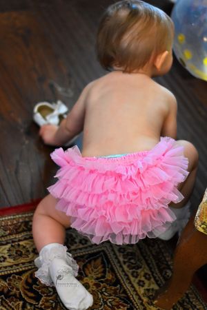 A baby in a pink tutu crawls across an ornate rug in a series of progressive movement shots.