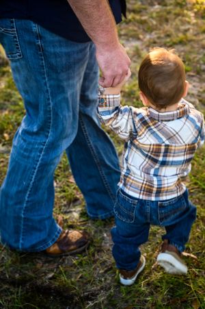 A sequence of photos showing a parent helping a small child in plaid shirt take first steps on grass.