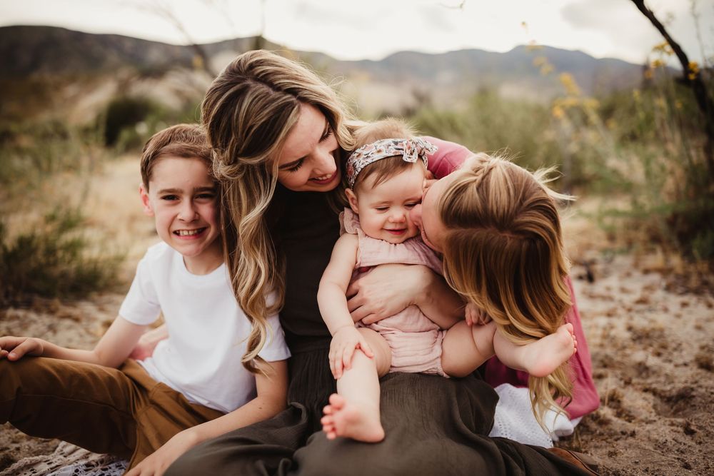Family enjoying playful moments together in an outdoor desert setting with mountains in the background.