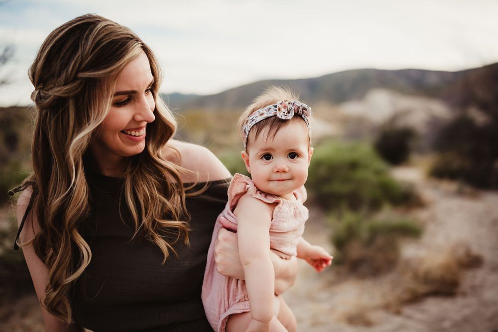 Candid family portraits in natural desert setting with soft lighting and muted earth tones.