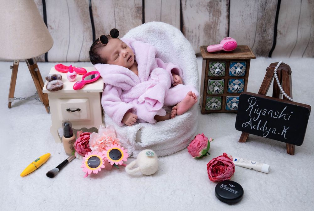 Sleeping newborn girl in studio prop setup with soft pink styling during newborn photoshoot in Hyderabad