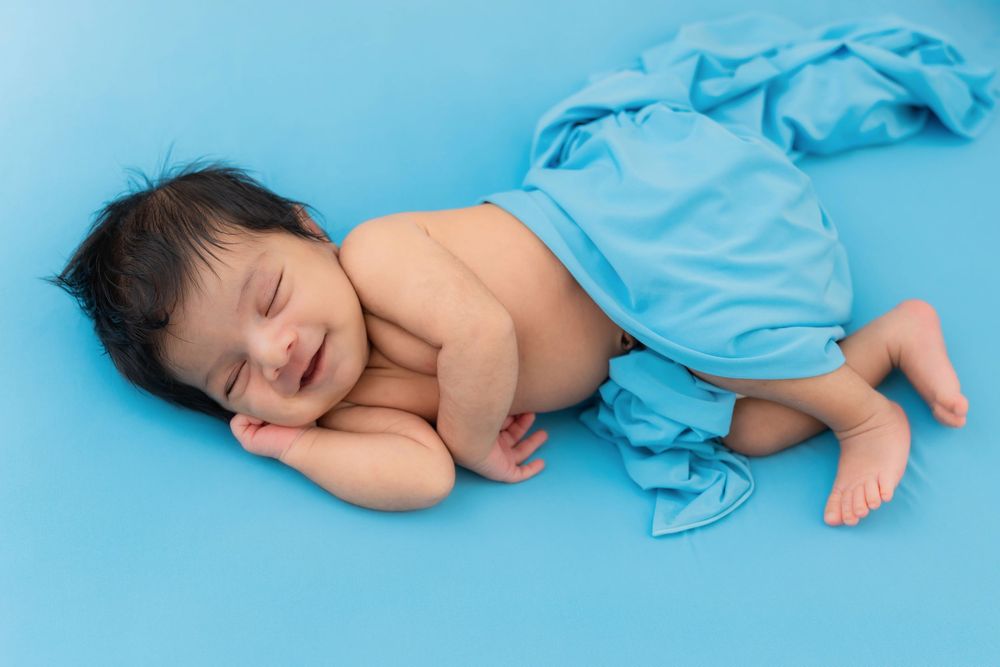 Sleeping newborn baby lying on blue backdrop during studio newborn photoshoot in Hyderabad
