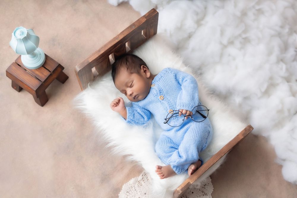 Sleeping newborn baby boy styled with blue props during studio newborn photoshoot in Hyderabad