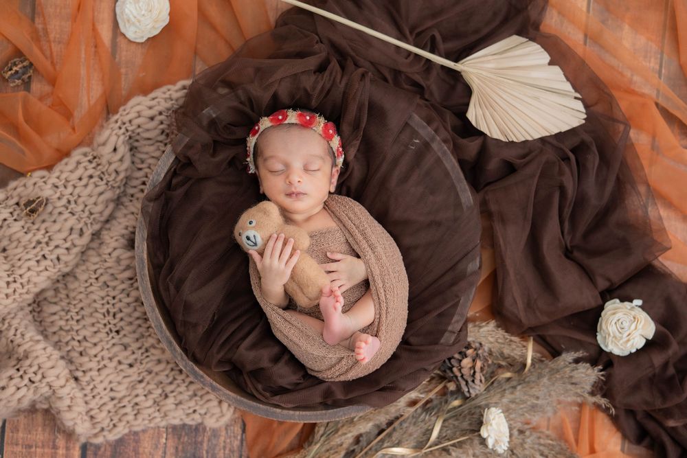 Newborn baby girl sleeping in brown theme setup during studio newborn photoshoot in Hyderabad