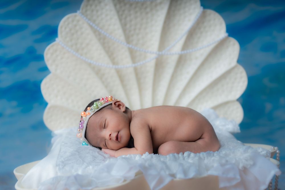 Sleeping newborn baby girl posed in shell prop at studio newborn photoshoot in Hyderabad
