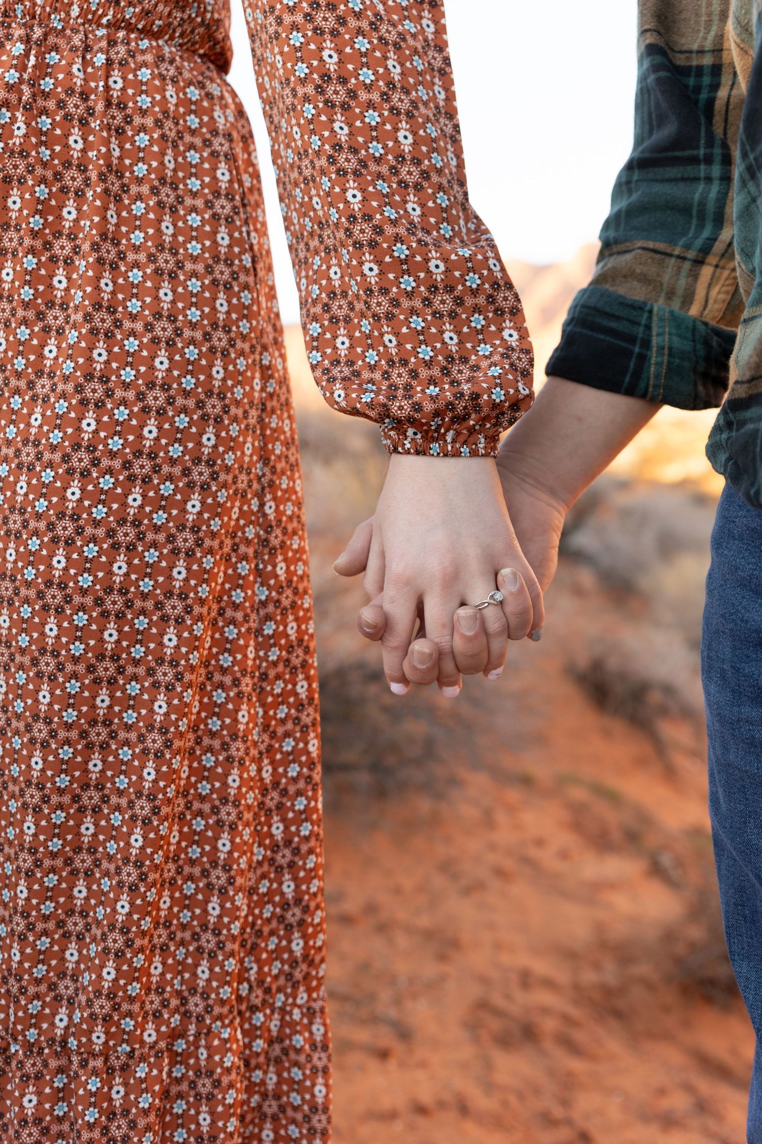 close up of a couple holding hands showing up engagement ring